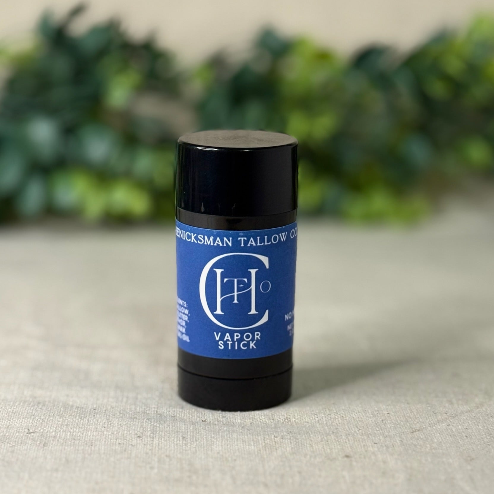 Vapor stick with blue label on a textured surface with greenery in the background
