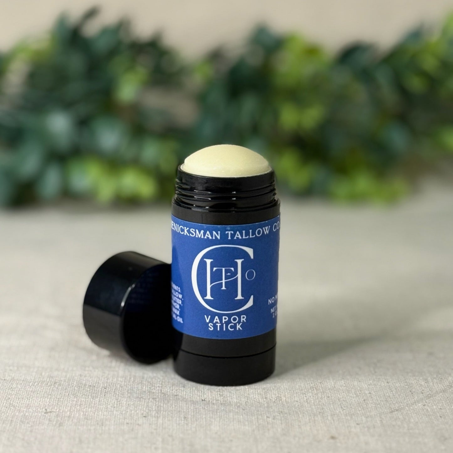 Vapor stick with blue label on a light surface with greenery in the background