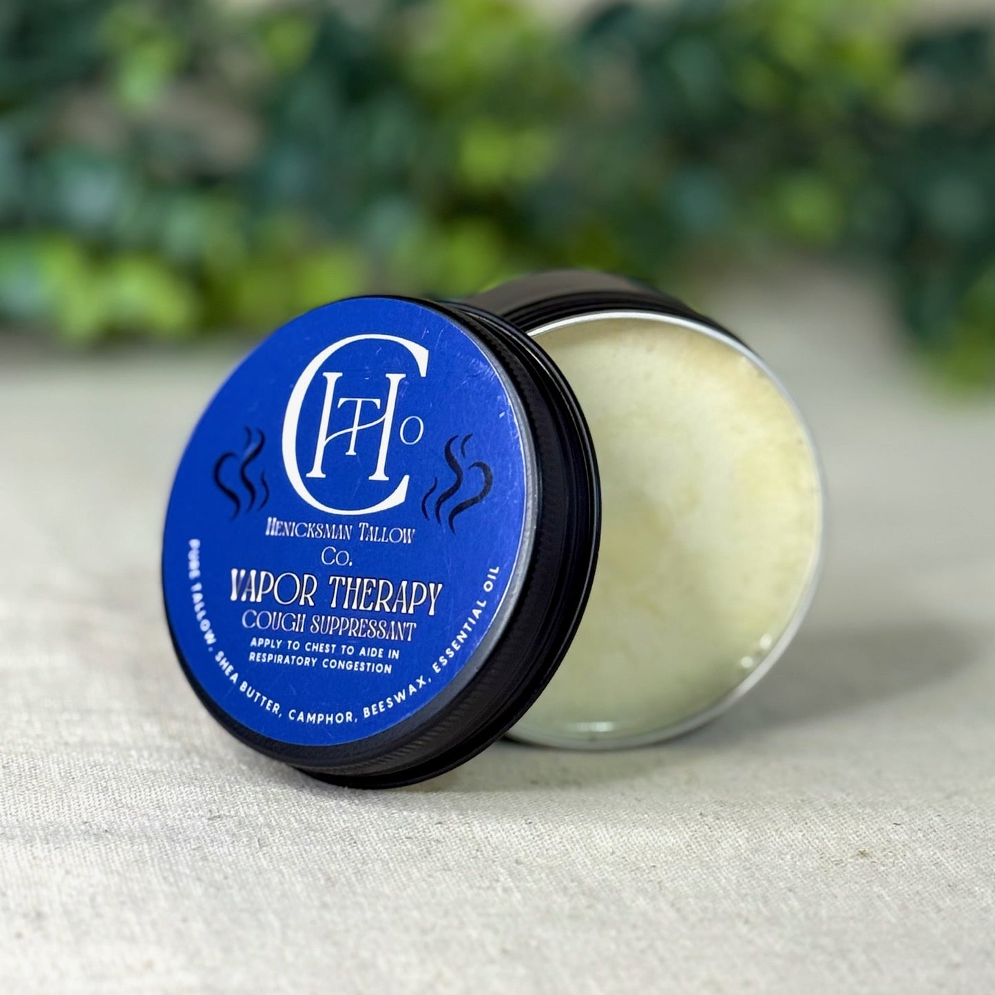 Vapor therapy product with blue label on a textured surface with greenery in the background
