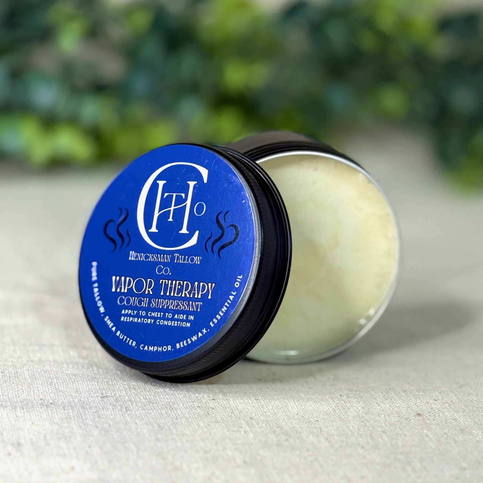 Vapor therapy product with blue label on a textured surface with greenery in the background