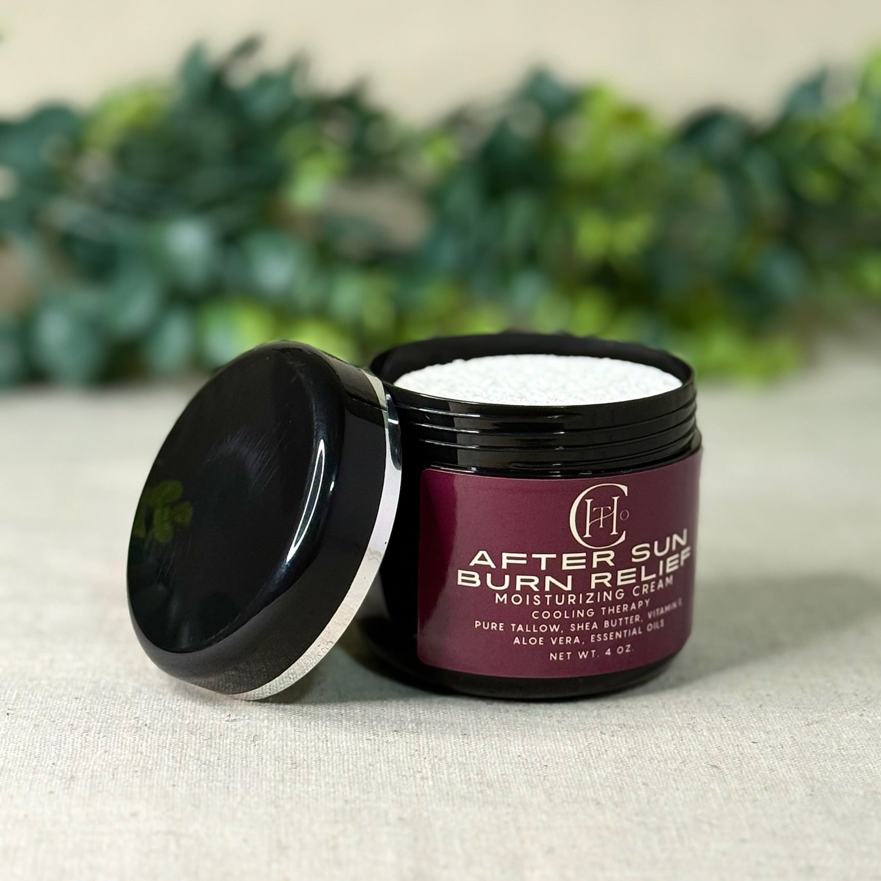 Open jar of after sun burn relief cream with a blurred green plant background