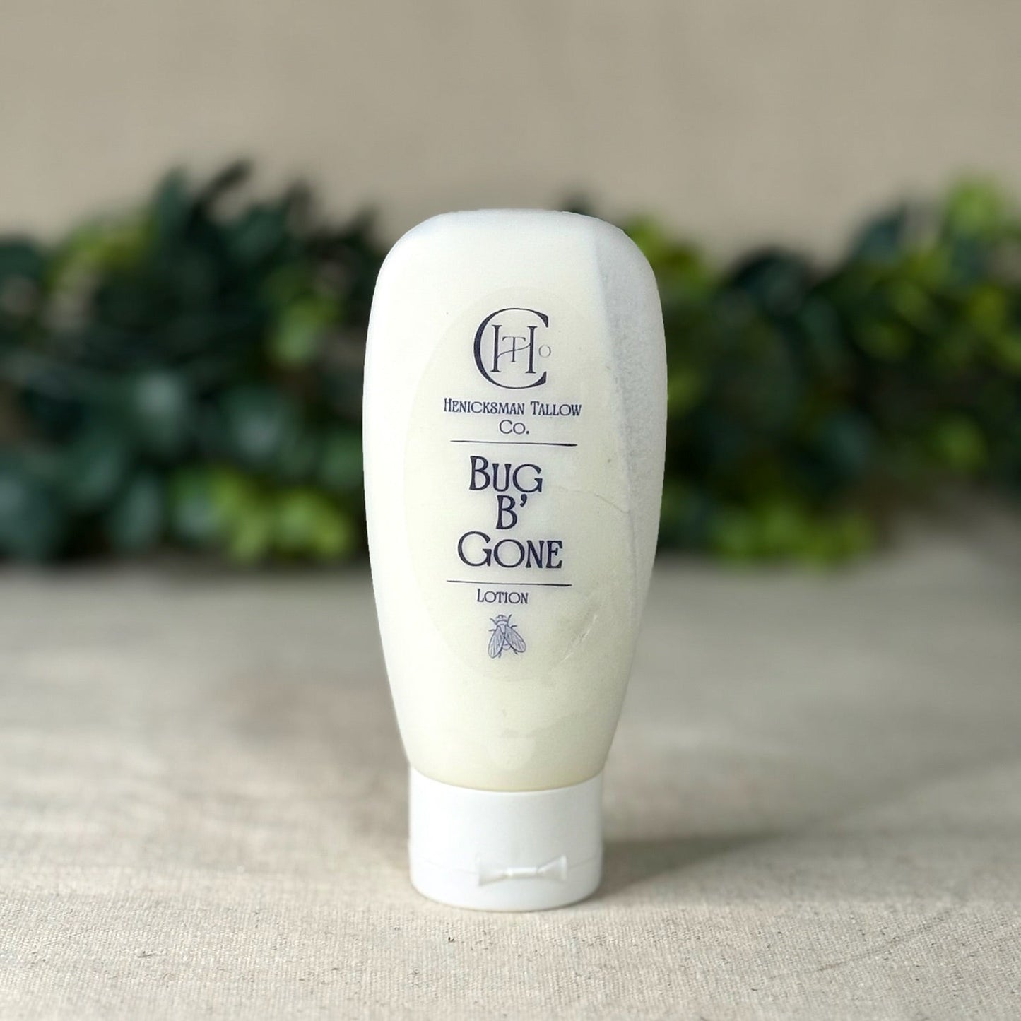 Tube of 'Bug B Gone' lotion on a neutral background with greenery.