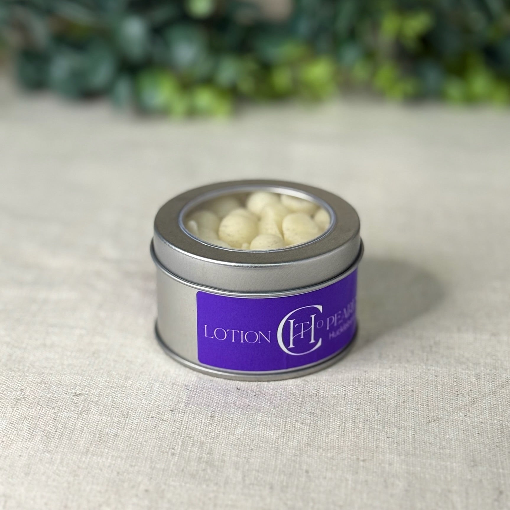 Small silver tin with white contents on a textured surface with greenery in the background