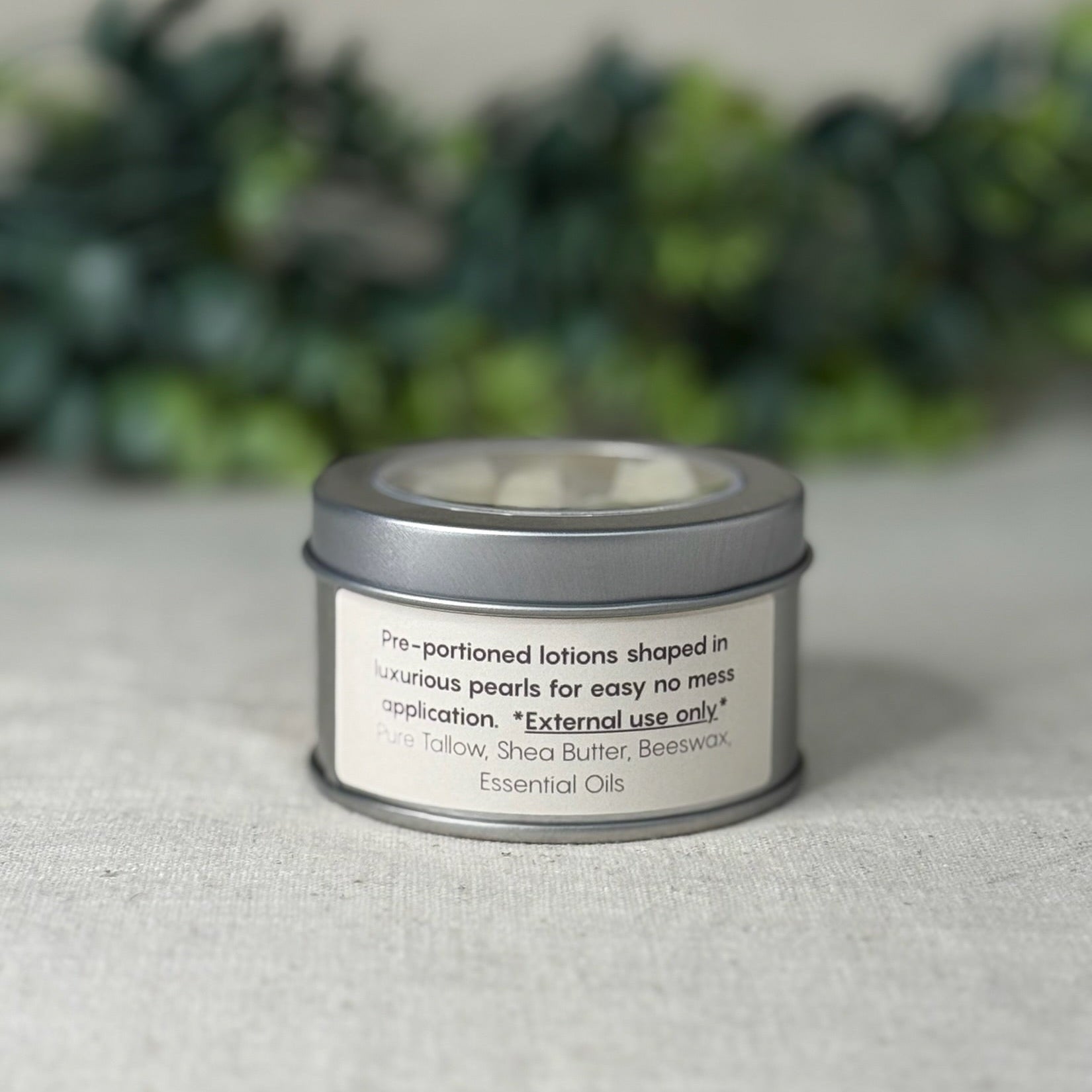 Tin container with a label on a textured surface with greenery in the background