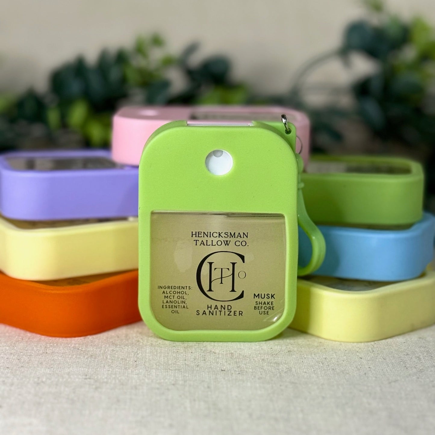 Green hand sanitizer bottle with colorful caps on a textured surface