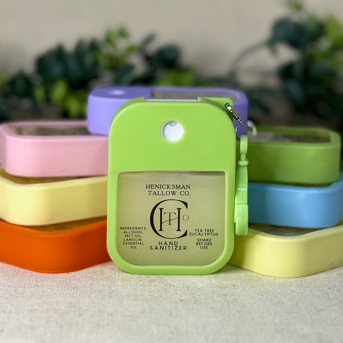 Colorful hand sanitizer bottles with a green one in the foreground on a white surface.